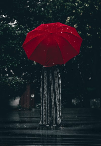 女人拿着红雨伞站在树在白天
